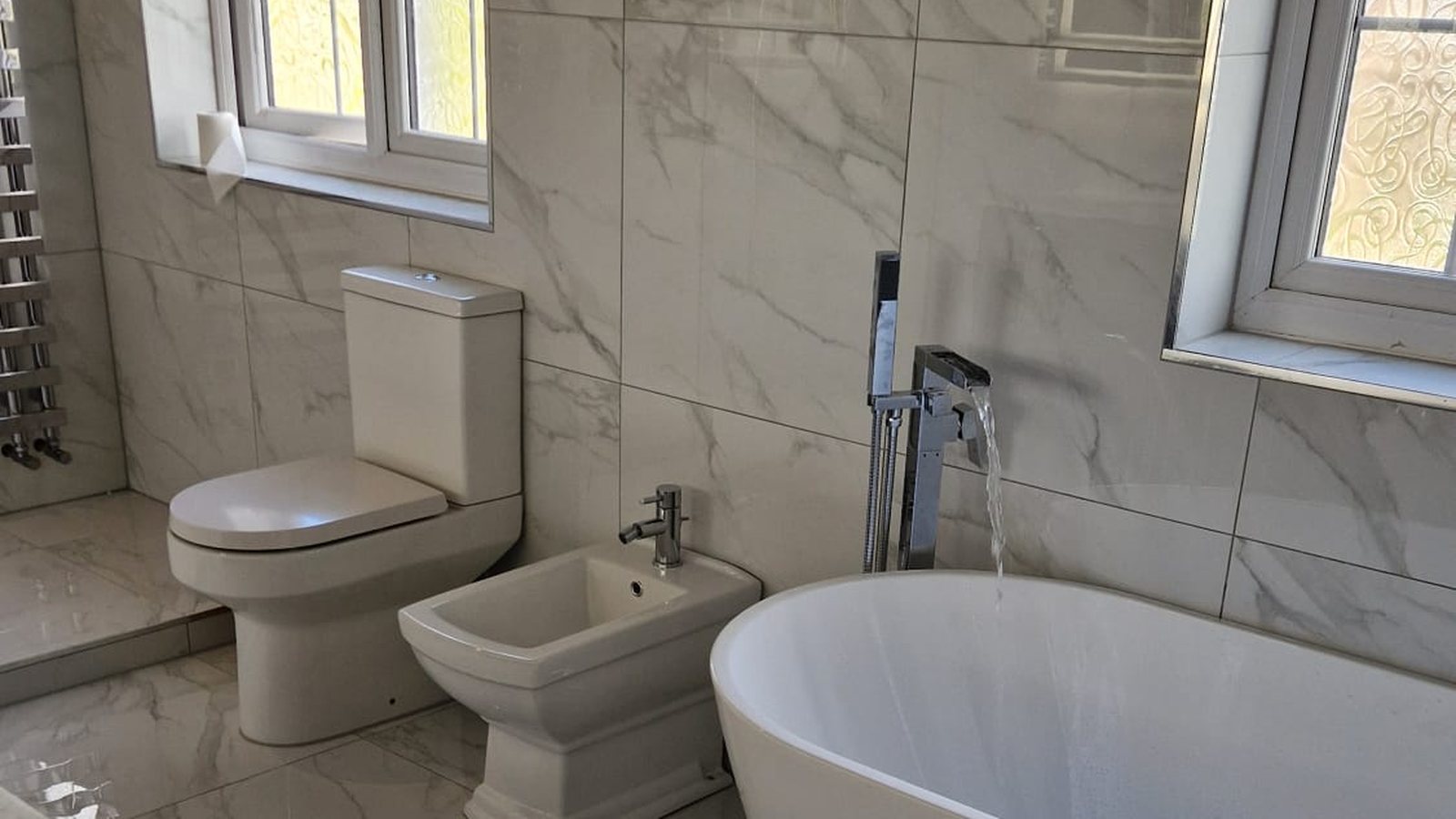 Marble bathroom with freestanding bath and polished marble floor by AG Signature Renovation